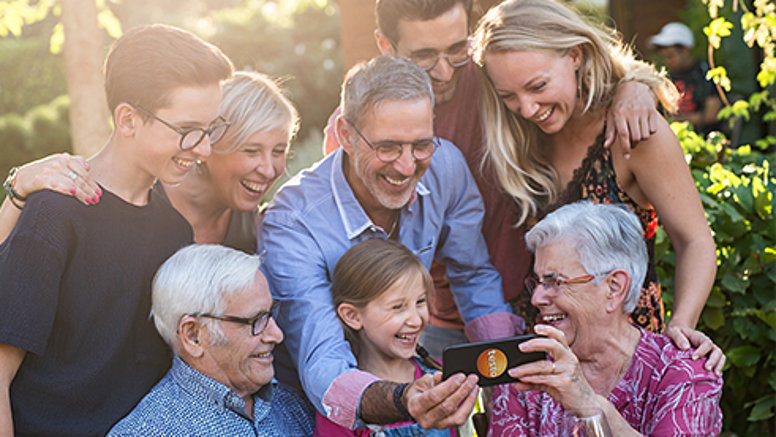 Mehr Zeit mit der Familie Verschiedene Generationen genießen ihre Freizeit, lachen und schauen auf ein Smartphone.